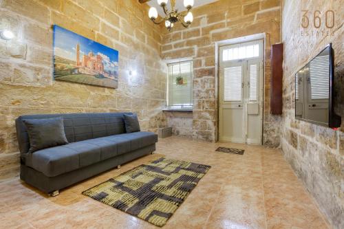 a living room with a couch in a stone wall at Authentic Townhouse with backyard in Sliema by 360 Estates in Sliema