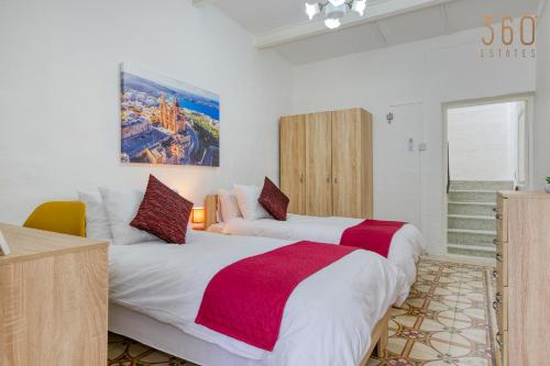 two beds in a room with white walls at Authentic Townhouse with backyard in Sliema by 360 Estates in Sliema
