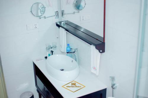 ein Badezimmer mit einem weißen Waschbecken und einem Spiegel in der Unterkunft Hotel New Riviera bukavu in Bukavu