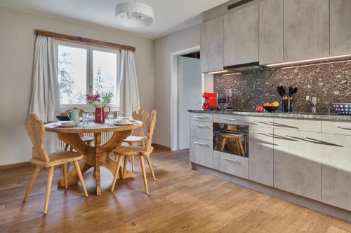 a kitchen with a wooden table and a dining room at Chesa Madrisa in St. Moritz
