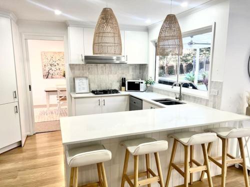 a kitchen with a white counter and some stools at SERENITY STAYS Mount Martha Mornington Peninsula in Mount Martha