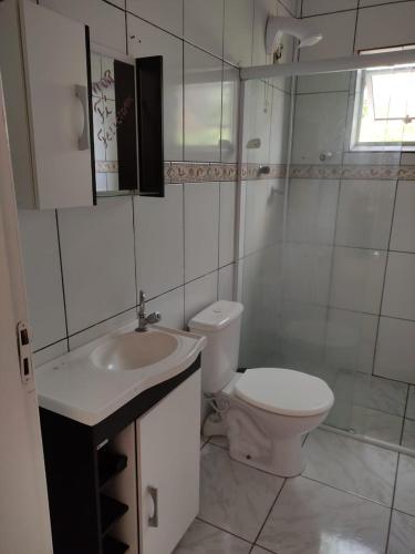 a white bathroom with a toilet and a sink at Casa mobiliada privativa in Caiçara