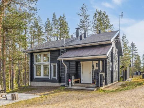 a black house with a white door in the woods at Holiday Home Uuvana by Interhome in Äkäslompolo