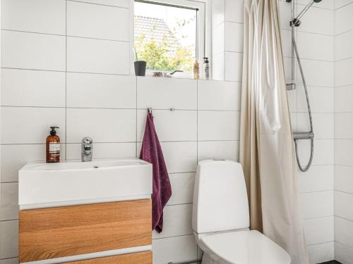 a bathroom with a sink and a toilet and a window at Villa Haveliden by Interhome in Sölvesborg