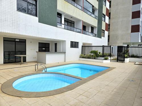 a swimming pool in front of a building at Apartamento vista mar Atalaia todos quartos climatizados in Aracaju