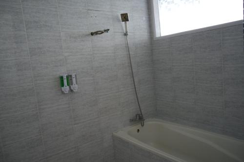 a bathroom with a shower with a tub and a sink at Tiara Bunga Hotel & Villa in Balige