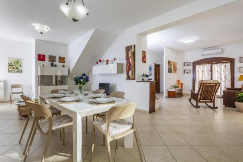 a dining room and living room with a white table and chairs at Villa Di Mauro in Viagrande