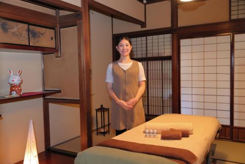 a woman standing in a room with a bed at Honjin Hiranoya Kachoan in Takayama