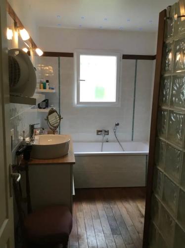une salle de bain avec une baignoire, un lavabo et une fenêtre dans l'établissement Maison avec piscine, à Saint-Sulpice