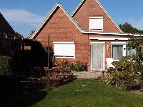 a brick house with white windows and a yard at Haus Gartenidylle in Wesselburen
