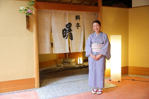 a woman wearing a kimono standing in a room at Honjin Hiranoya Kachoan in Takayama