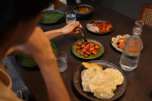 a table topped with plates of food with people eating at Bhadra - The Estate Villa in Wayanad