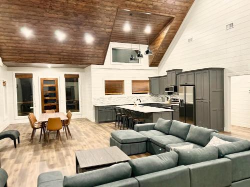 a large living room with a couch and a kitchen at Shady Days Cabin Stylish 3BR Retreat with Hot Tub & Outdoor Kitchen - 5 Mins to Hochatown in Broken Bow