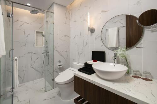 a bathroom with a sink and a toilet and a mirror at Mövenpick Living West Hanoi in Hanoi