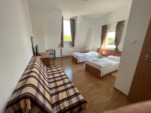 a hotel room with two beds and a couch at Pokoje gościnne Słowiańska Słońsk (restauracja) in Słońsk