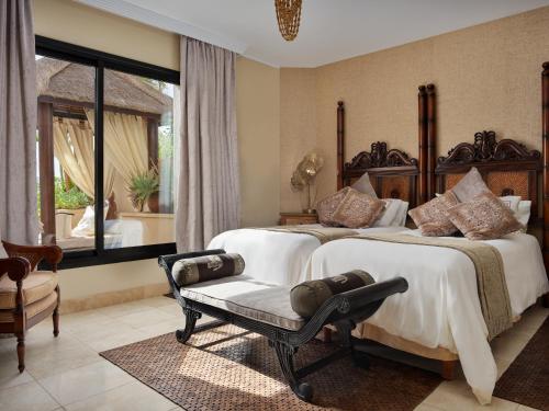 a bedroom with two beds and a chair and a window at Royal Garden Villas, Luxury Hotel in Adeje