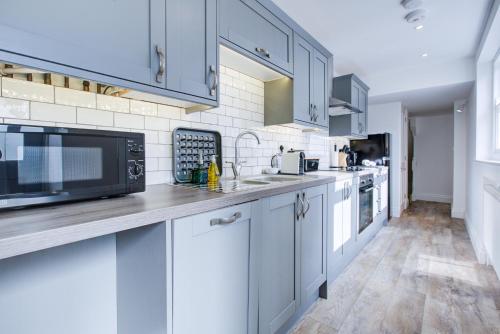 a kitchen with blue cabinets and a counter top at Luxury 2 Bed Apartment with Stunning Sea View Steps from Old Town and Dreamland in Margate