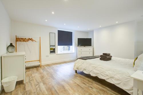 a white bedroom with a bed and a television at Luxury 2 Bed Apartment with Stunning Sea View Steps from Old Town and Dreamland in Margate
