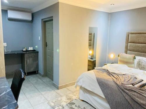 a bedroom with a bed and a desk and a sink at President Guest Lodge in Louis Trichardt