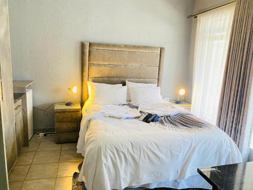 a bed with white sheets and pillows in a bedroom at President Guest Lodge in Louis Trichardt