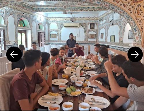 a group of people sitting at a table eating food at Hotel Radhika Haveli, Mandawa in Mandāwa