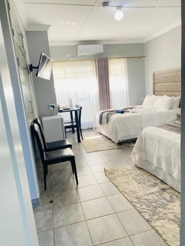 a bedroom with two beds and a chair and a table at President Guest Lodge in Louis Trichardt