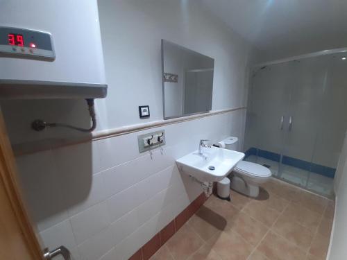 Un baño con lavabo, inodoro y espejo. en Habitación Tomillar, en Lumpiaque