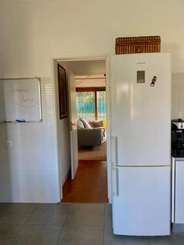 a kitchen with a white refrigerator and a living room at A Casa da Carrasqueira, Sesimbra in Sesimbra