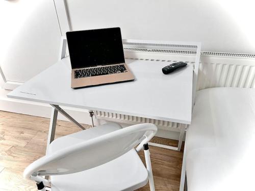 a laptop computer sitting on a white desk with a chair at Cozy Fully Equipped Loft Studio City Centre in Maidstone