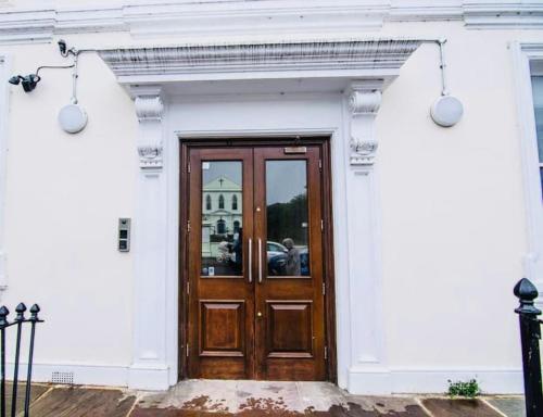 a white building with a wooden door on it at Cozy Fully Equipped Loft Studio City Centre in Maidstone