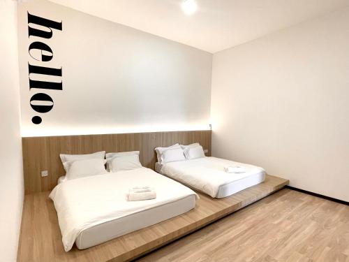 two beds in a room with a sign on the wall at the Eins at the Frohaus in Tawau