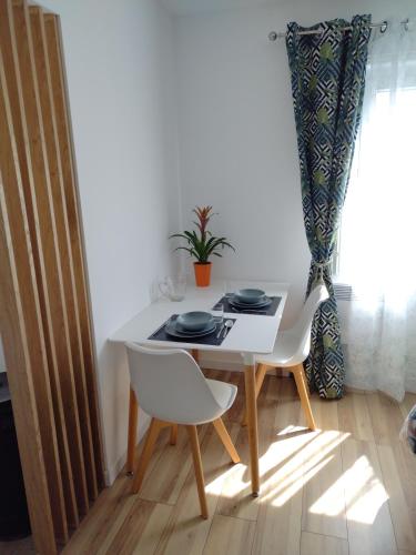 a white table with two chairs and a plant on it at Studio indépendant location courte durée à proximité du Lycée International in Saint-Germain-en-Laye