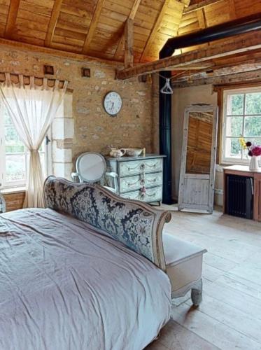 une chambre avec un lit et une horloge au mur dans l'établissement Romantic cottage in garden of Château de La Motte-Feuilly, à La Motte-Feuilly