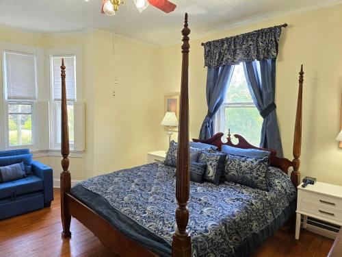 a bedroom with a canopy bed and a blue couch at Newly Renovated Historic 6-BR Manor plus 1-BR Apt, Where Timeless Elegance Meets Modern Luxury in Onancock