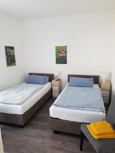 a bedroom with two beds and a chair at Gästehaus Harzstraße in Schladen