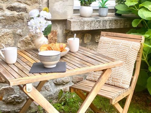 a wooden picnic table with a bowl of food and a plate of bread at T2 lumineux - rénové- - Centre historique Dinan- Parking - Terrasse in Dinan