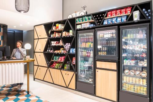 a woman standing at a counter in a store with a refrigerator at Aparthotel Adagio Paris Centre Tour Eiffel in Paris