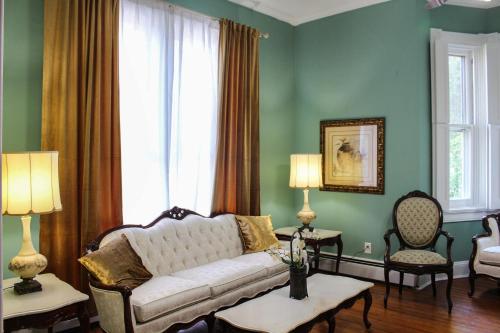 a living room with a white couch and a window at Newly Renovated Historic 6-BR Manor plus 1-BR Apt, Where Timeless Elegance Meets Modern Luxury in Onancock