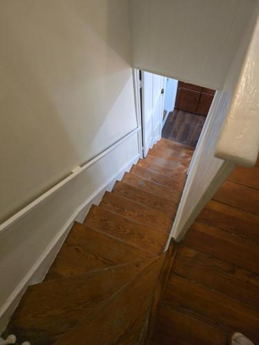 a stairway with wooden floors and white walls at Newly Renovated Historic 6-BR Manor plus 1-BR Apt, Where Timeless Elegance Meets Modern Luxury in Onancock
