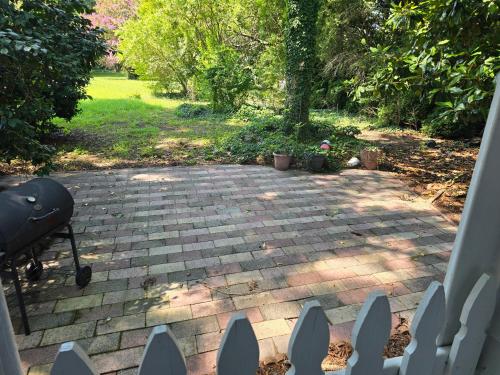 a backyard patio with a grill and a brick yard at Newly Renovated Historic 6-BR Manor plus 1-BR Apt, Where Timeless Elegance Meets Modern Luxury in Onancock