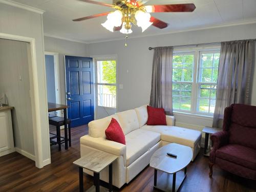 a living room with a white couch and a ceiling fan at Newly Renovated Historic 6-BR Manor plus 1-BR Apt, Where Timeless Elegance Meets Modern Luxury in Onancock