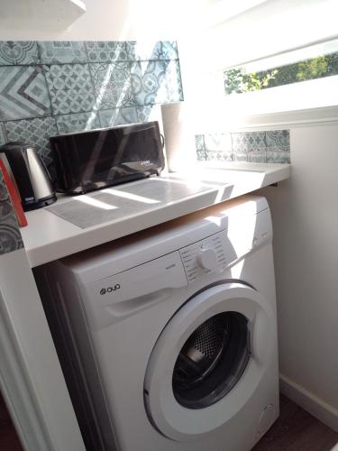 a laundry room with a washing machine under a counter at Studio indépendant location courte durée à proximité du Lycée International in Saint-Germain-en-Laye