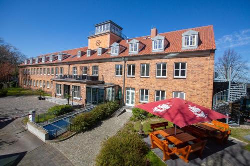 a large brick building with a red umbrella in front of it at Hotel Hafenresidenz Stralsund in Stralsund