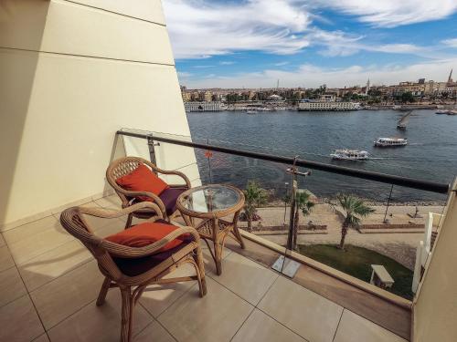 a balcony with chairs and a view of the water at Mövenpick Resort Aswan in Aswan