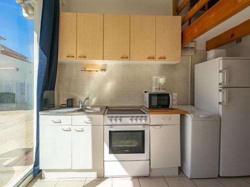 La cuisine est équipée d'appareils électroménagers blancs et d'un réfrigérateur. dans l'établissement Studio Nauzan by Interhome, à Saint-Palais-sur-Mer