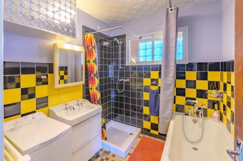 a bathroom with yellow and black tiles and a tub and sink at Sixties Forever - une immersion années 60 in Aubenton