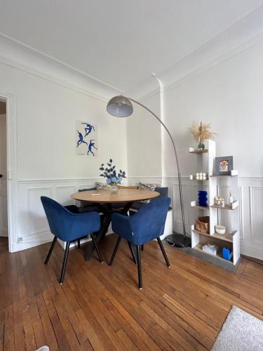 une salle à manger avec une table et des chaises bleues dans l'établissement Appartement Cosy et agréable, à Colombes