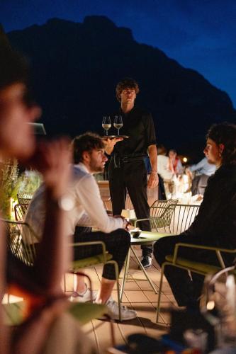 a group of people sitting around a table with glasses of wine at Hotel Promessi Sposi in Malgrate