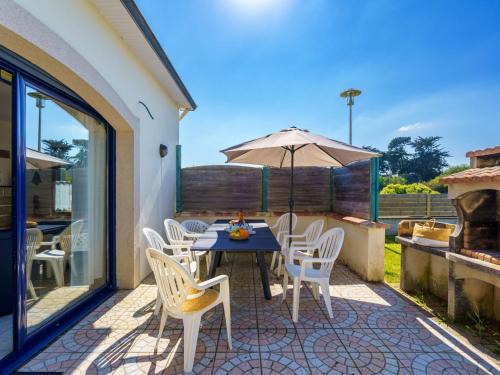 un patio avec une table, des chaises et un parasol dans l'établissement Holiday Home La mouette bleue by Interhome, à Loctudy