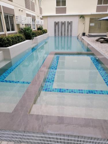 a swimming pool in a building with blue water at Homey Staycation in Silang Cavite! Fullerton Suites Puting Kahoy - near CKS, AUP, PNPA, in Puting Kahoy